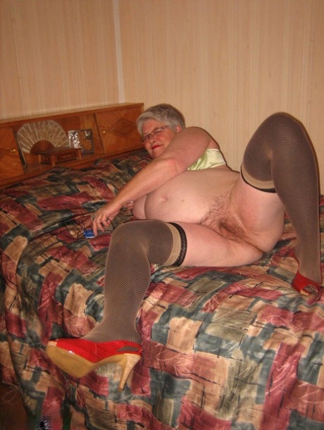 Fat granny Girdle Goddess pets her femininity after stripping to hosiery on her bed