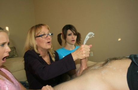 Mature blonde in glasses teaching her young adult friends how to stroke a big manhood