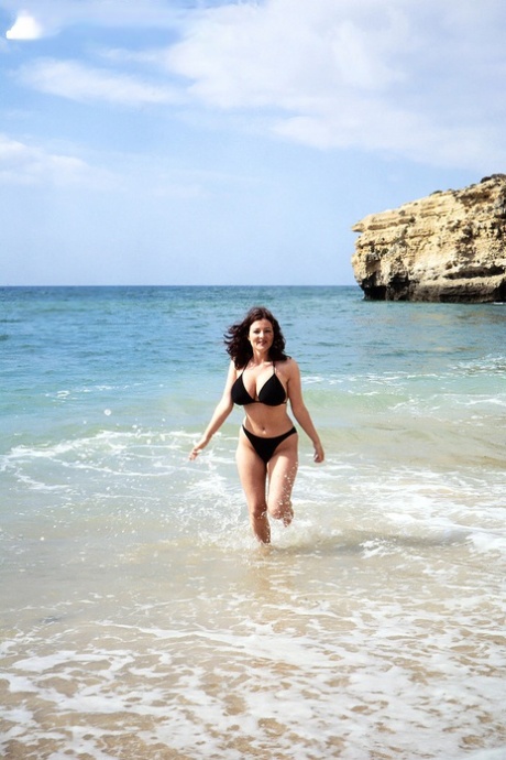 Brunette MATURE WOMAN Lorna Morgan releases her nice melons from bikini on a beach