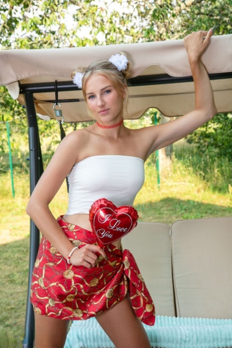 Beautiful blonde young adult Nana gets natural on a bench swing while wearing a choker