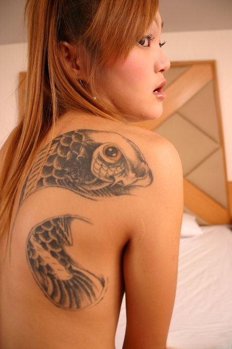 Skinny Asian young adult with slender body Apple stripping and revealing big tattoo