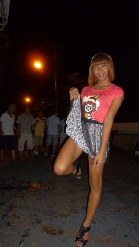 Red-haired Asian ladyboy lifts dress up to flash manhood in public place