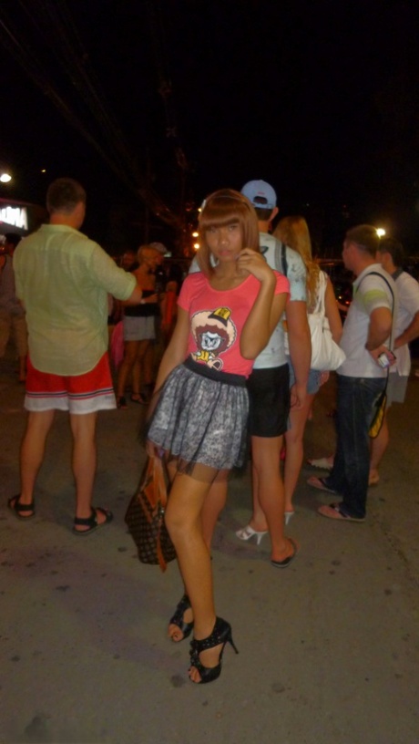 Red-haired Asian ladyboy lifts dress up to flash manhood in public place