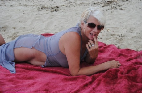 Beautiful busty mature Dimonty poses fully clothed in sheer dress at the beach