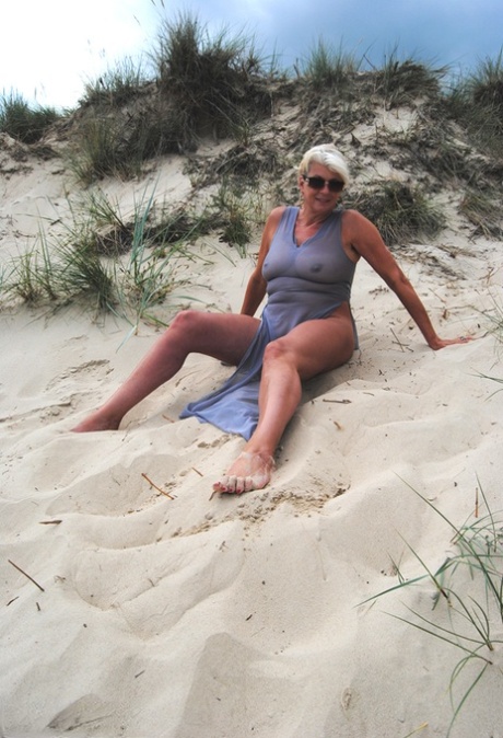 Beautiful busty mature Dimonty poses fully clothed in sheer dress at the beach