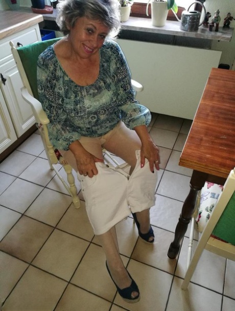 Horny granny Caro sticks a banana inside her natural femininity on kitchen chair