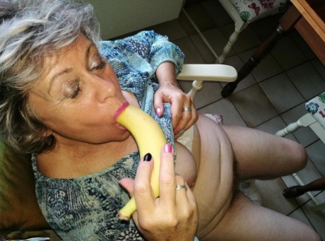 Horny granny Caro sticks a banana inside her natural femininity on kitchen chair